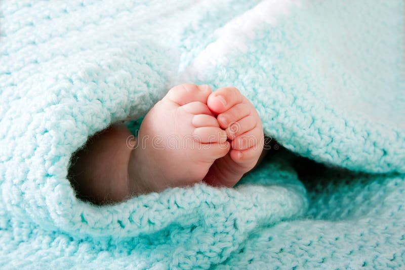Dvě roztomilé malé dítě nohy zabalené v modré, zelené aqua pletené deky.