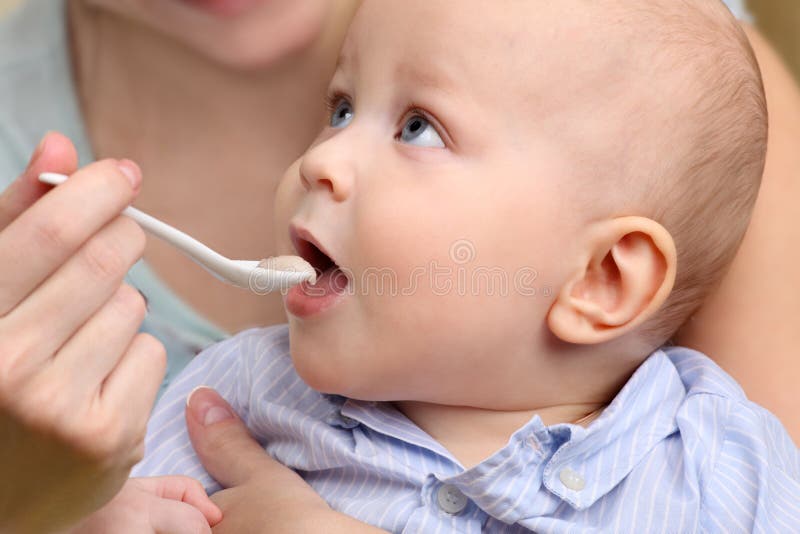 Baby food, baby eating. Mother feeding her baby boy by spoon. royalty free stock image Baby food, baby eating. Mother feeding her baby boy by spoon. royalty free stock image