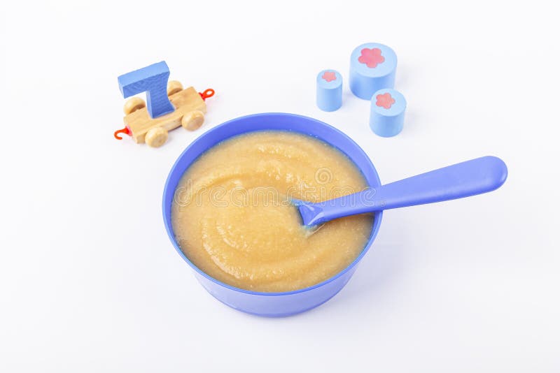 Baby food. Fresh homemade applesauce. Blue bowl with fruit puree on fabric and kids toys on table. The concept of proper nutrition