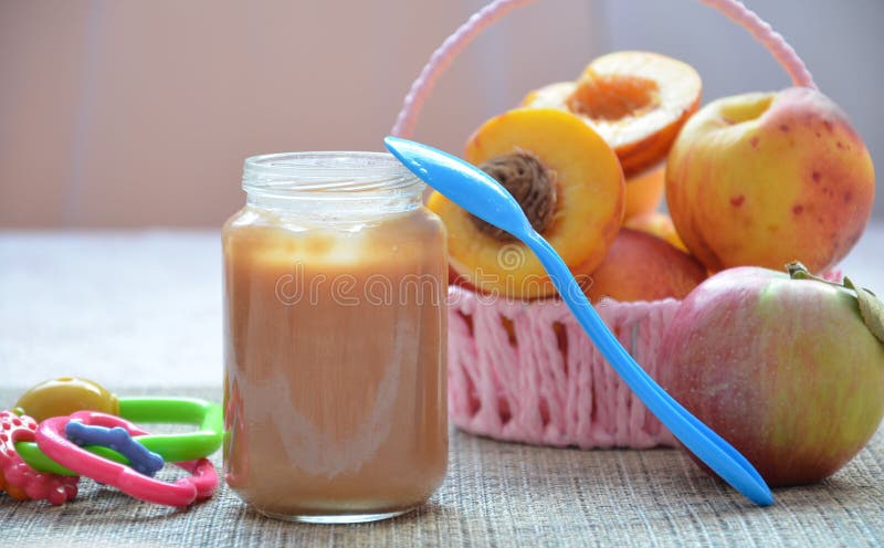 Baby food, baby fruit mashed in a glass jar, peach, beautiful peaches in a basket, children`s toy. apple