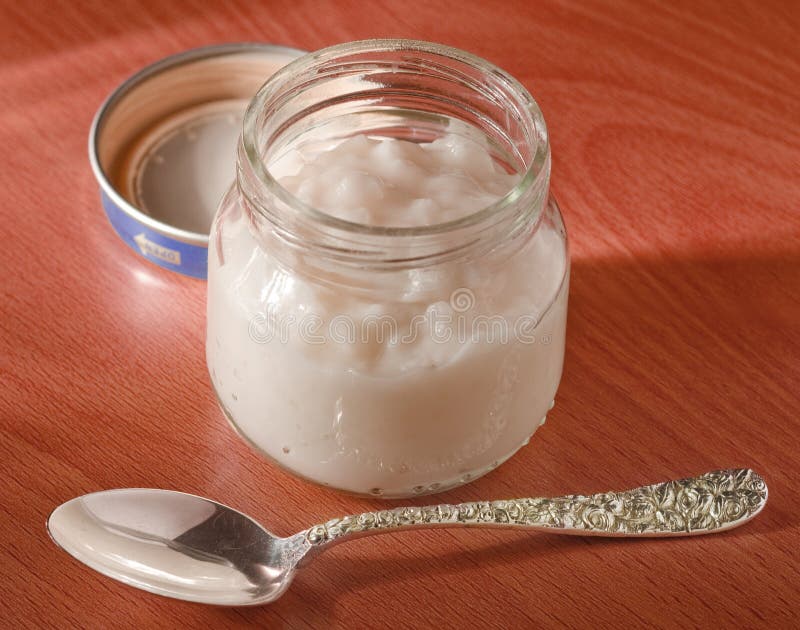 Jar of baby food on red wood with silver spoon. Jar of baby food on red wood with silver spoon