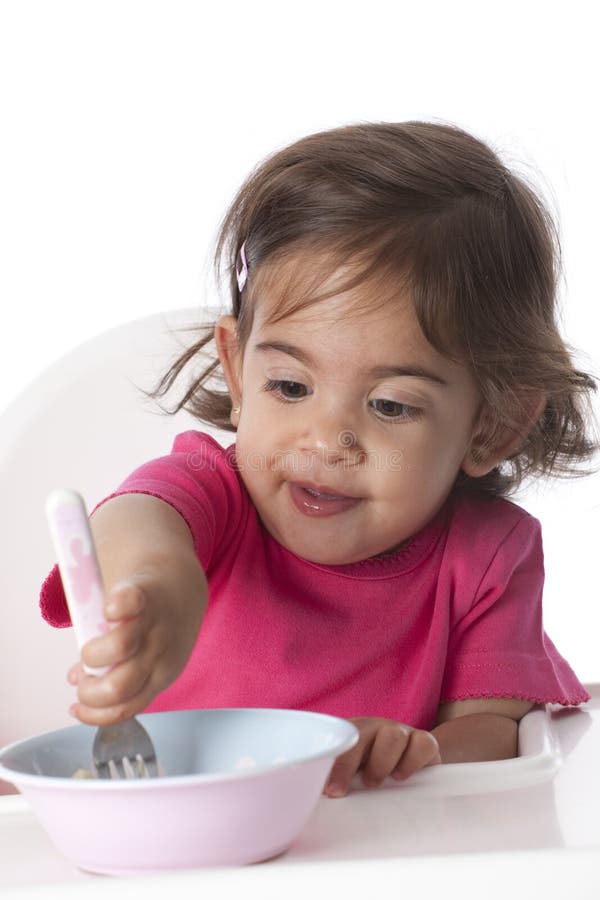Baby girl is eating by herself stock photography