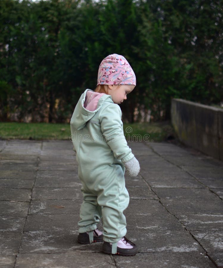 Baby girl in mint soft shell bodysuit is playing in a back yard in spring. stock images