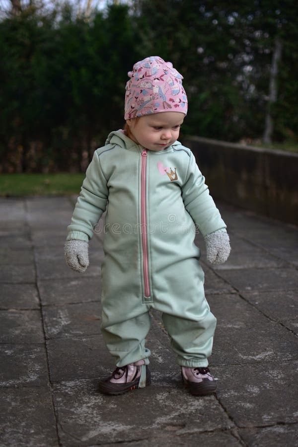 Baby girl in mint soft shell bodysuit is playing in a back yard in spring. stock image