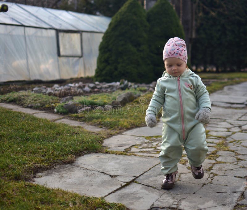 Baby girl in mint soft shell bodysuit is playing in a back yard in spring. stock photo