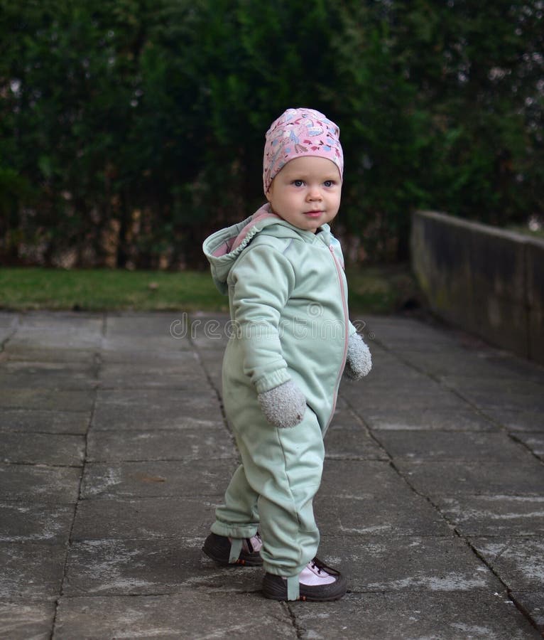 Baby girl in mint soft shell bodysuit is playing in a back yard in spring. royalty free stock photography