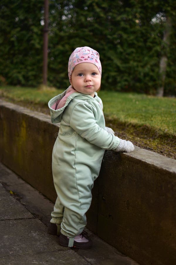 Baby girl in mint soft shell bodysuit is playing in a back yard in spring. royalty free stock photos
