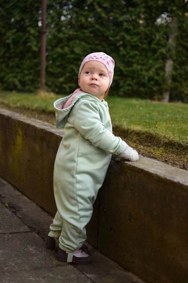 Baby girl in mint soft shell bodysuit is playing in a back yard in spring. royalty free stock image
