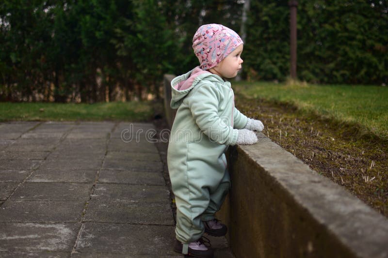 Baby girl in mint soft shell bodysuit is playing in a back yard in spring. stock photo
