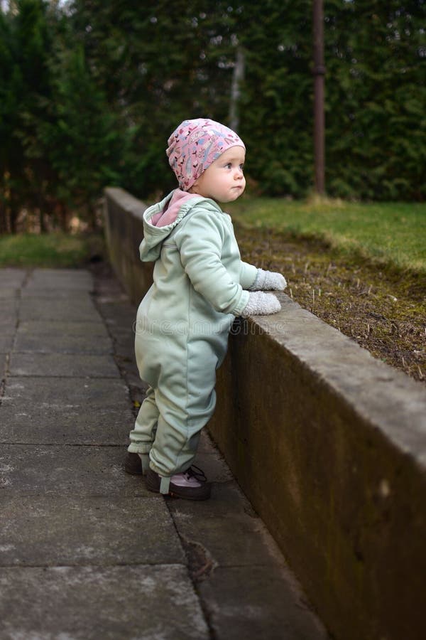 Baby girl in mint soft shell bodysuit is playing in a back yard in spring. stock photos