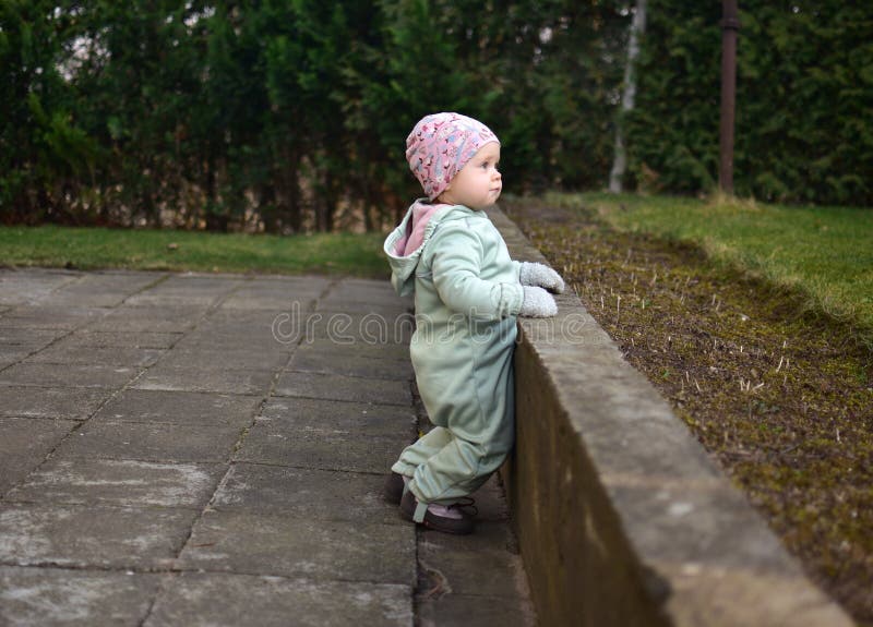 Baby girl in mint soft shell bodysuit is playing in a back yard in spring. stock photo