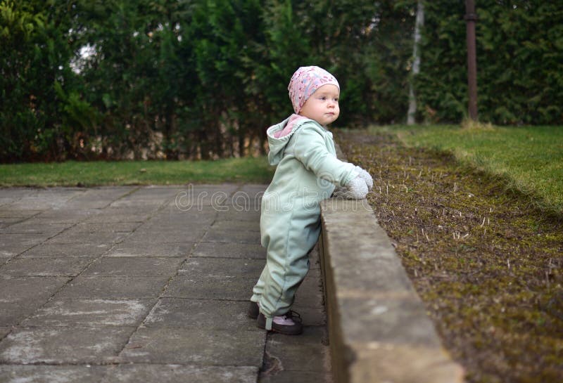 Baby girl in mint soft shell bodysuit is playing in a back yard in spring. royalty free stock photos