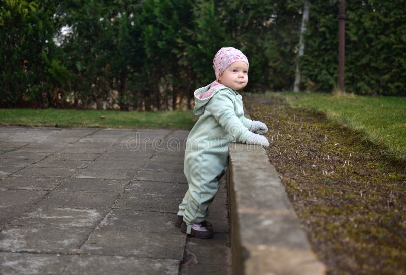 Baby girl in mint soft shell bodysuit is playing in a back yard in spring. royalty free stock images