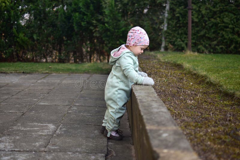 Baby girl in mint soft shell bodysuit is playing in a back yard in spring. royalty free stock photos