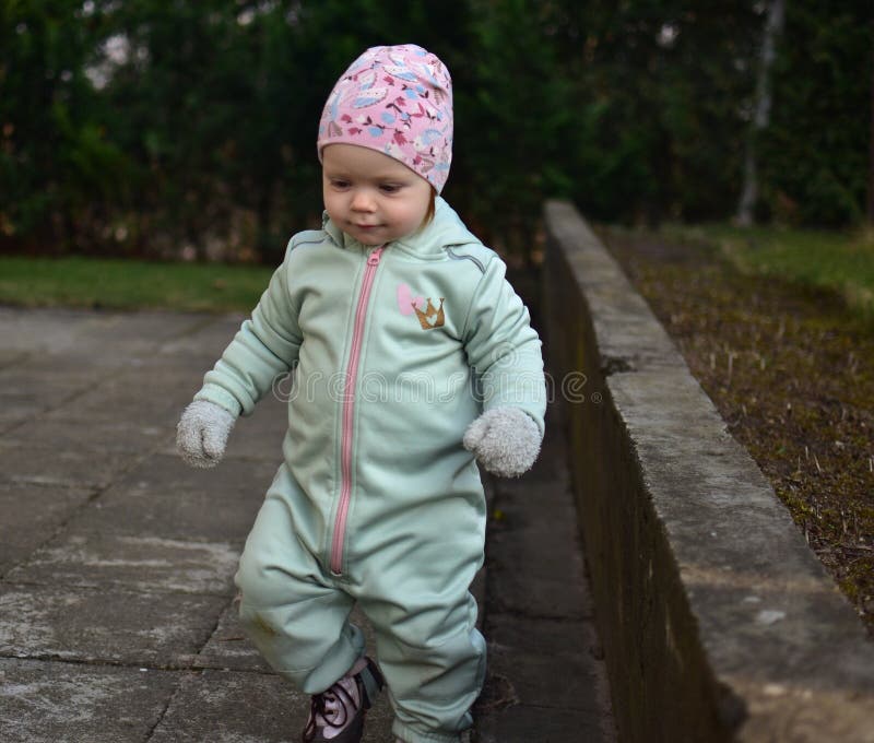 Baby girl in mint soft shell bodysuit is playing in a back yard in spring. stock photos