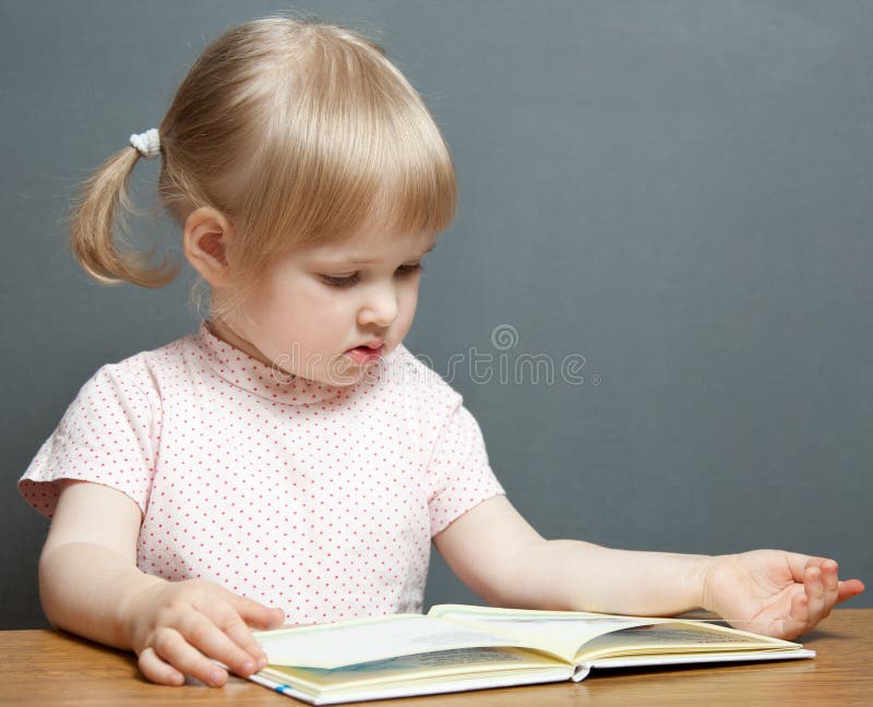The baby girl is reading the book stock photos The baby girl is reading the book stock photos