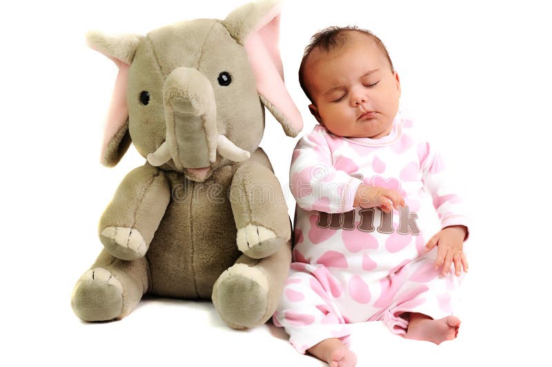 Baby girl with pink dots suite sitting and sleeping with gray elephant toy next to her. Baby girl with pink dots suite sitting and sleeping with gray elephant toy next to her