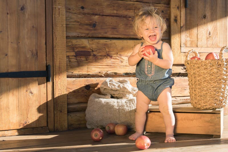 Baby Girl stands and Smiles near Wooden Barn