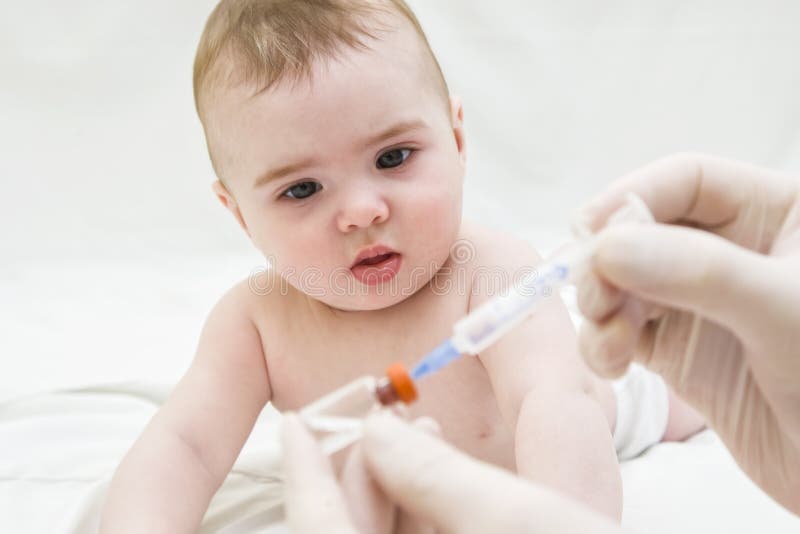 Baby girl is starring on syringe with vaccine stock photo Baby girl is starring on syringe with vaccine stock photo