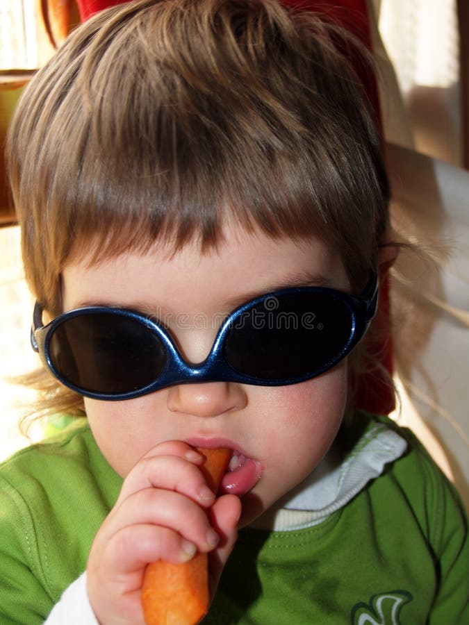 Baby girl with sunglasses and carrot