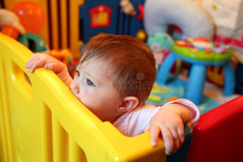 Baby girl thinking in a playpen