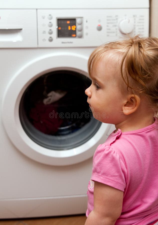 Baby girl and washing machine stock photo