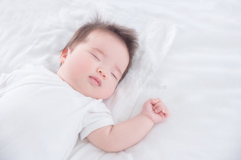 Baby girl wearing white cloth sleeping on white bed