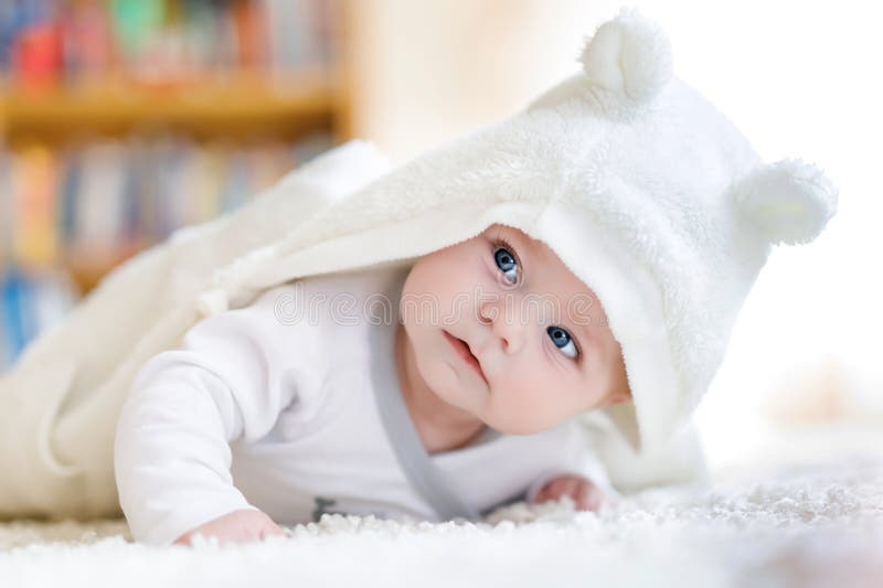 Baby girl wearing white towel or winter overal in white sunny bedroom