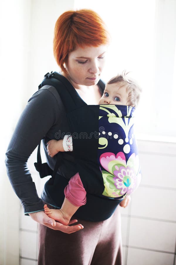 Baby held by his mother in a baby carrier stock photo Baby held by his mother in a baby carrier stock photo