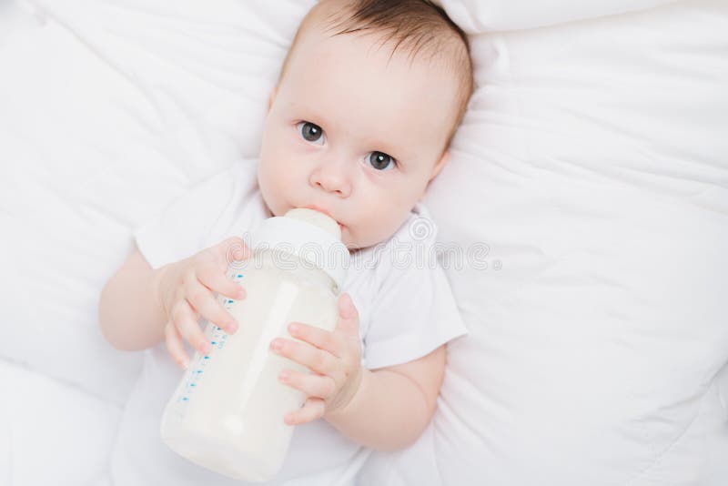 The Baby in His Crib Eats from a Bottle . Baby Food Copyspace . Artificial Feeding Stock Image