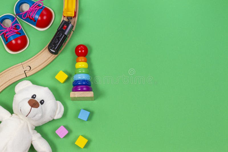 Baby kids toys background with toys train, colorful wooden blocks and plush teddy bear on light green background