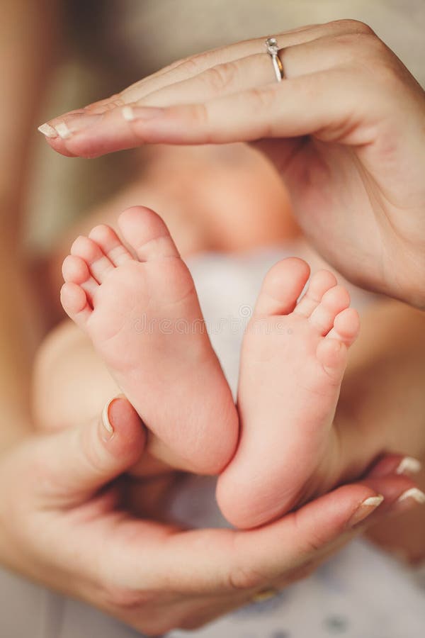 Baby legs. Newborn feet in the hands of her mother