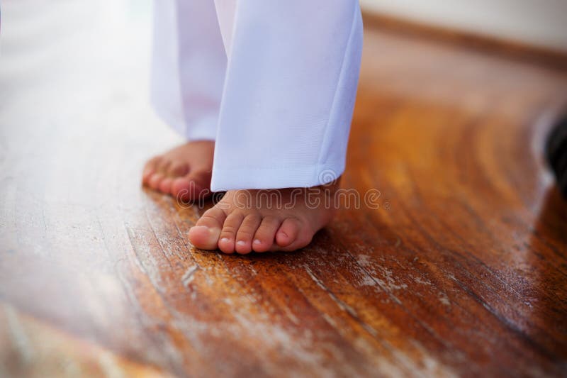 Baby legs in white pants on a wooden floor.