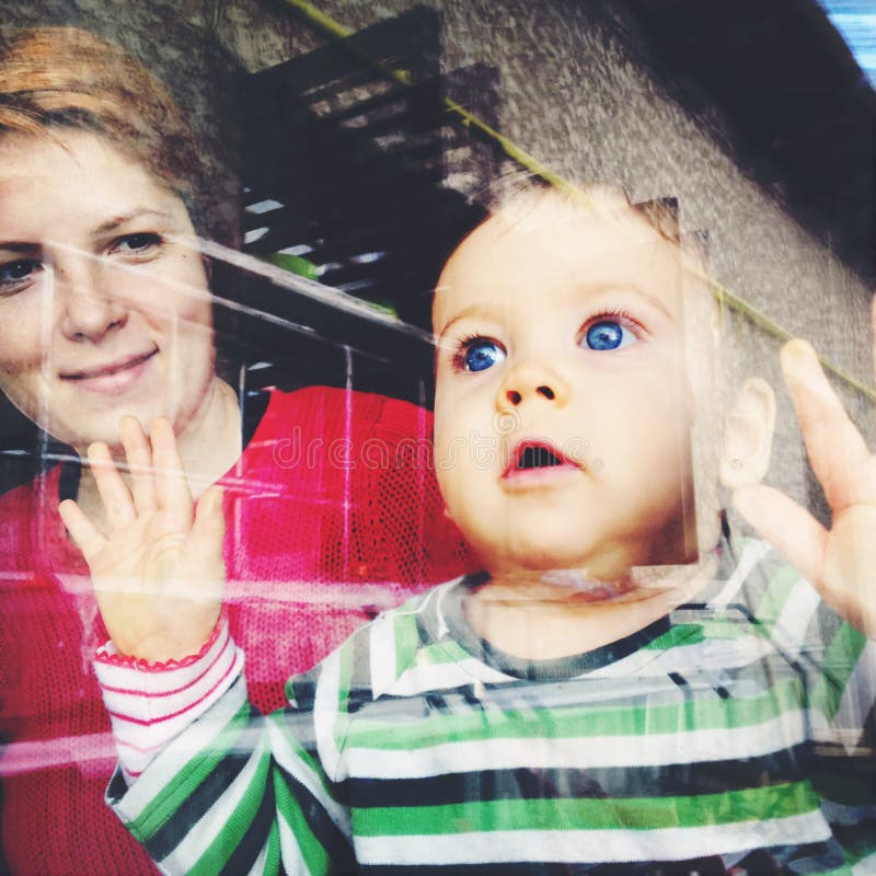 Baby looking through window stock image Baby looking through window stock image