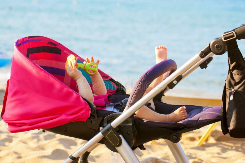 Baby lying in stroller on the beach