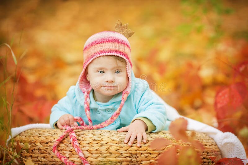 Baby with Down syndrome is resting in autumn forest. Baby with Down syndrome is resting in autumn forest