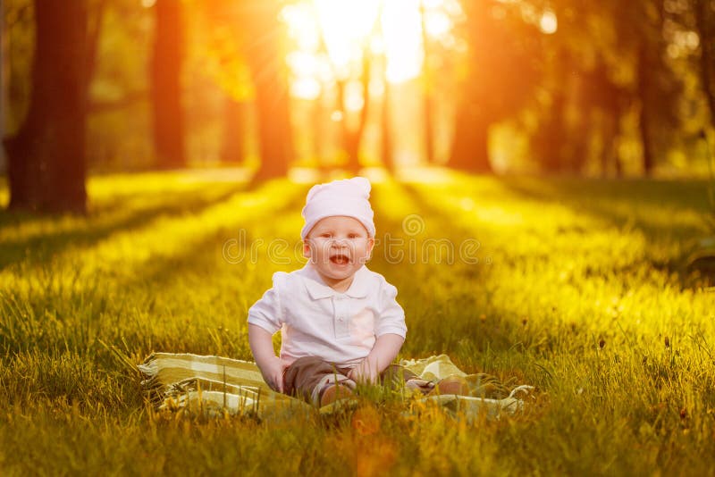 Baby in the park in the rays of sunset. Toddler on the nature outdoors. Backlight. Summertime family scene stock photo Baby in the park in the rays of sunset. Toddler on the nature outdoors. Backlight. Summertime family scene stock photo