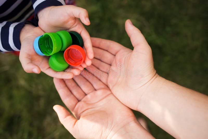 Baby puts plastic lids in mother`s hands. parent and his child collect cover. e. royalty free stock photos