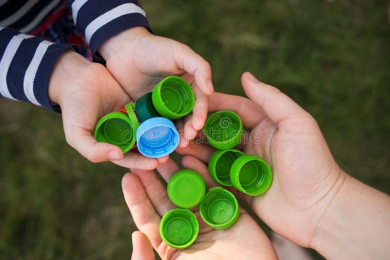 Baby puts plastic lids in mother`s hands. parent and his child collect cover. recyclable. royalty free stock images