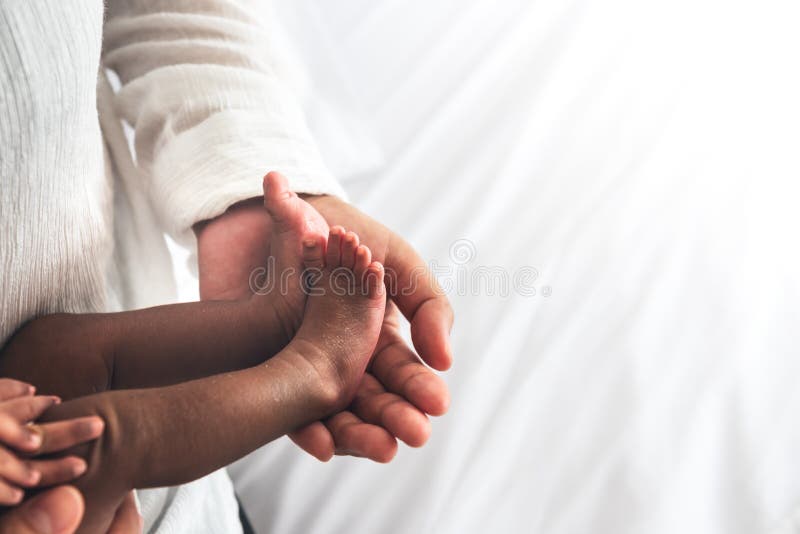 Baby`s foot of an African American, 12-day- old, Placed on the mother`s hand