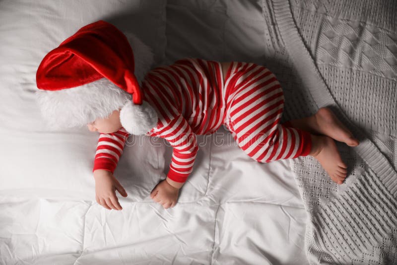 Baby in Santa Hat Sleeping on Bed with White Linens, Top View Stock