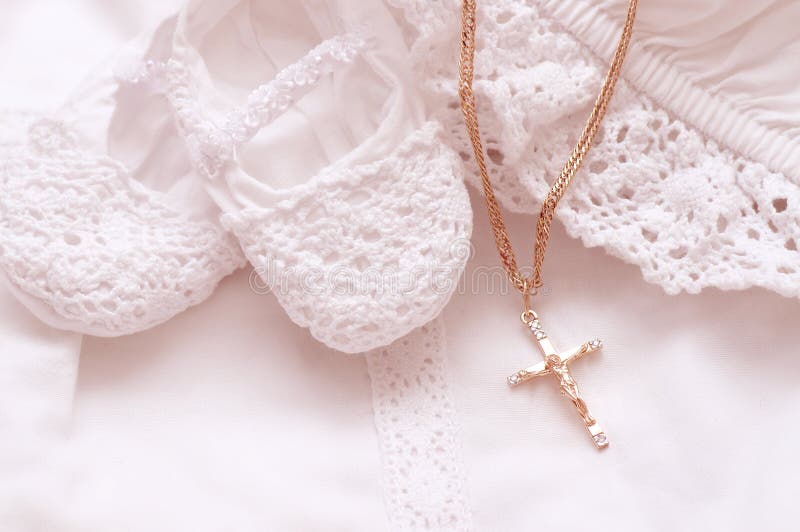 Baby shoes and white dress with golden cross