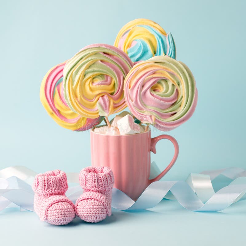 Baby shower decoration - it is a girl. Rainbow sweetness and knitted pink booties socks on blue background. First birthday, royalty free stock images Baby shower decoration - it is a girl. Rainbow sweetness and knitted pink booties socks on blue background. First birthday, royalty free stock images