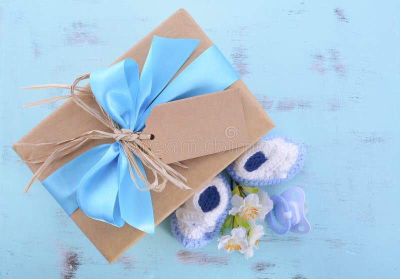 Baby shower Its a Boy natural wrap gift with gift box, baby booties and dummy on pale blue shabby chic rustic wood table.