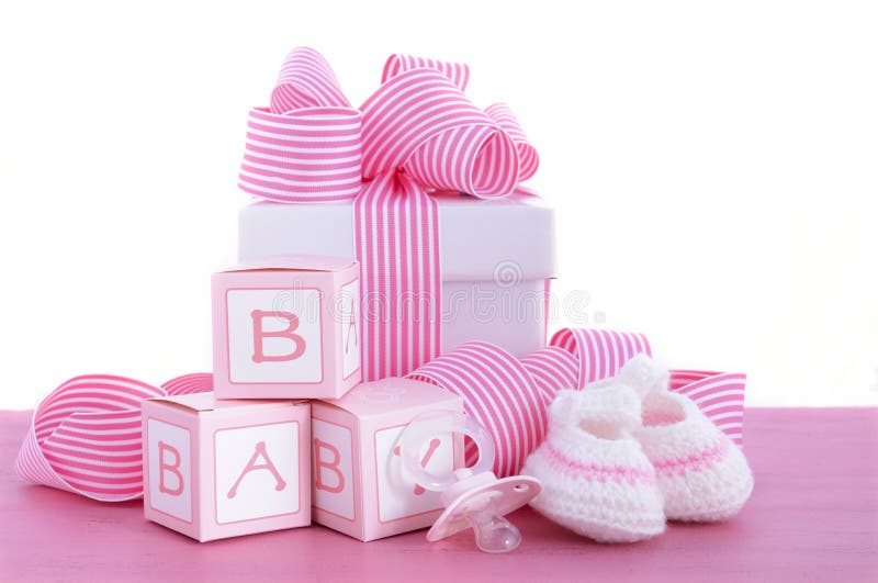 Baby shower Its a Girl pink gift with baby booties, dummy and gift box on pink shabby chic wood table.