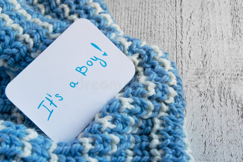 Baby shower `It`s a boy`, announcement card on cozy woolen blue blanket and space for text. New arrival in the family stock images Baby shower `It`s a boy`, announcement card on cozy woolen blue blanket and space for text. New arrival in the family stock images
