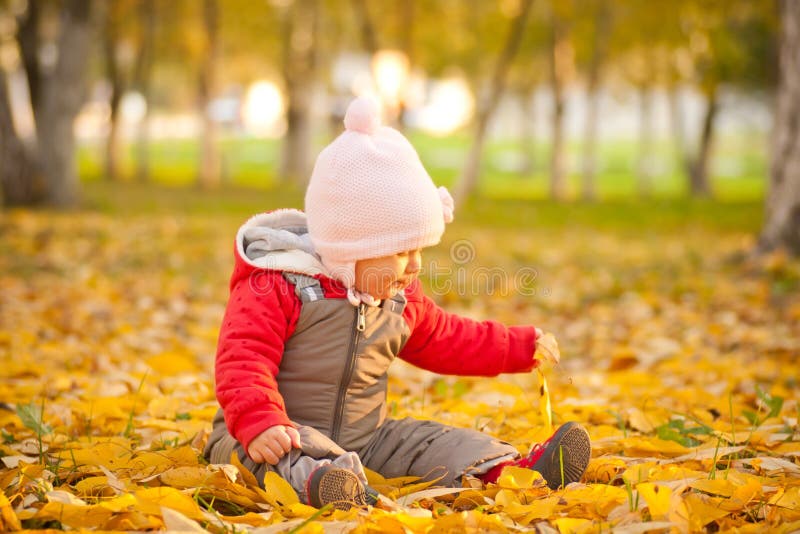 Baby sit on leafes in autumn park