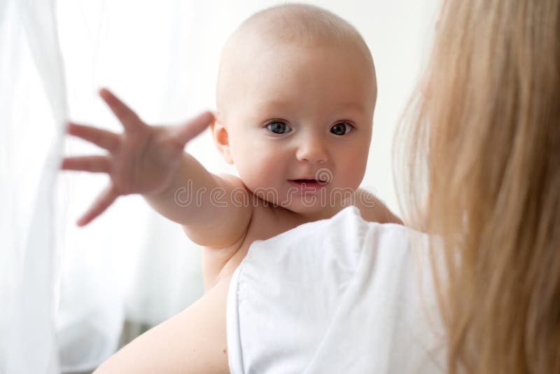 Baby of six months old in his mothers hands.