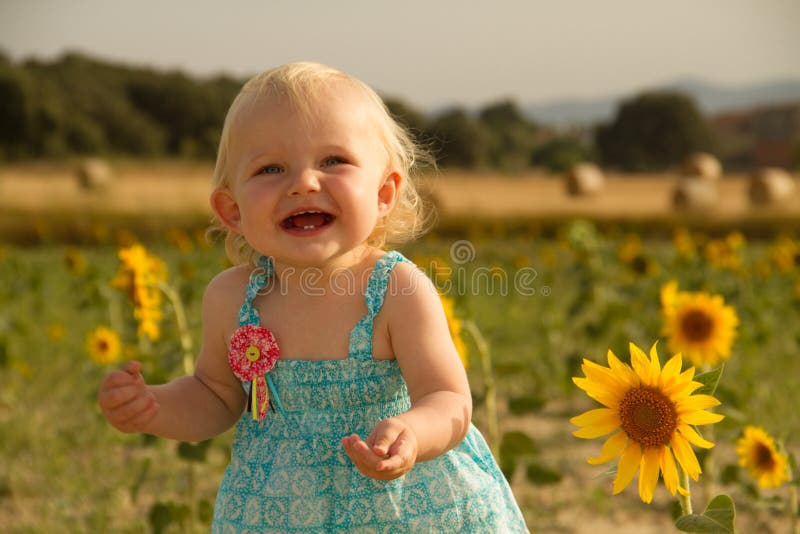 Baby standing next to sunflower
