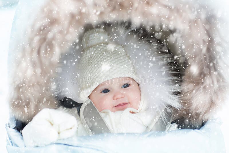 Baby in stroller in winter snow. Kid in pram